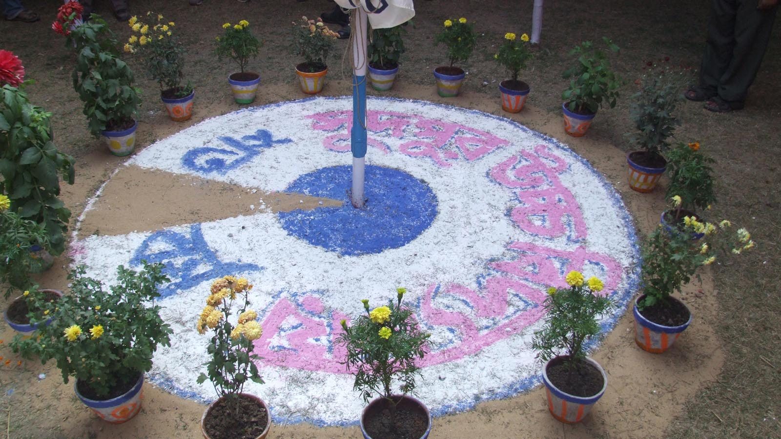 Traditional alpona floor art around the flagpole, decorated with marigold pots