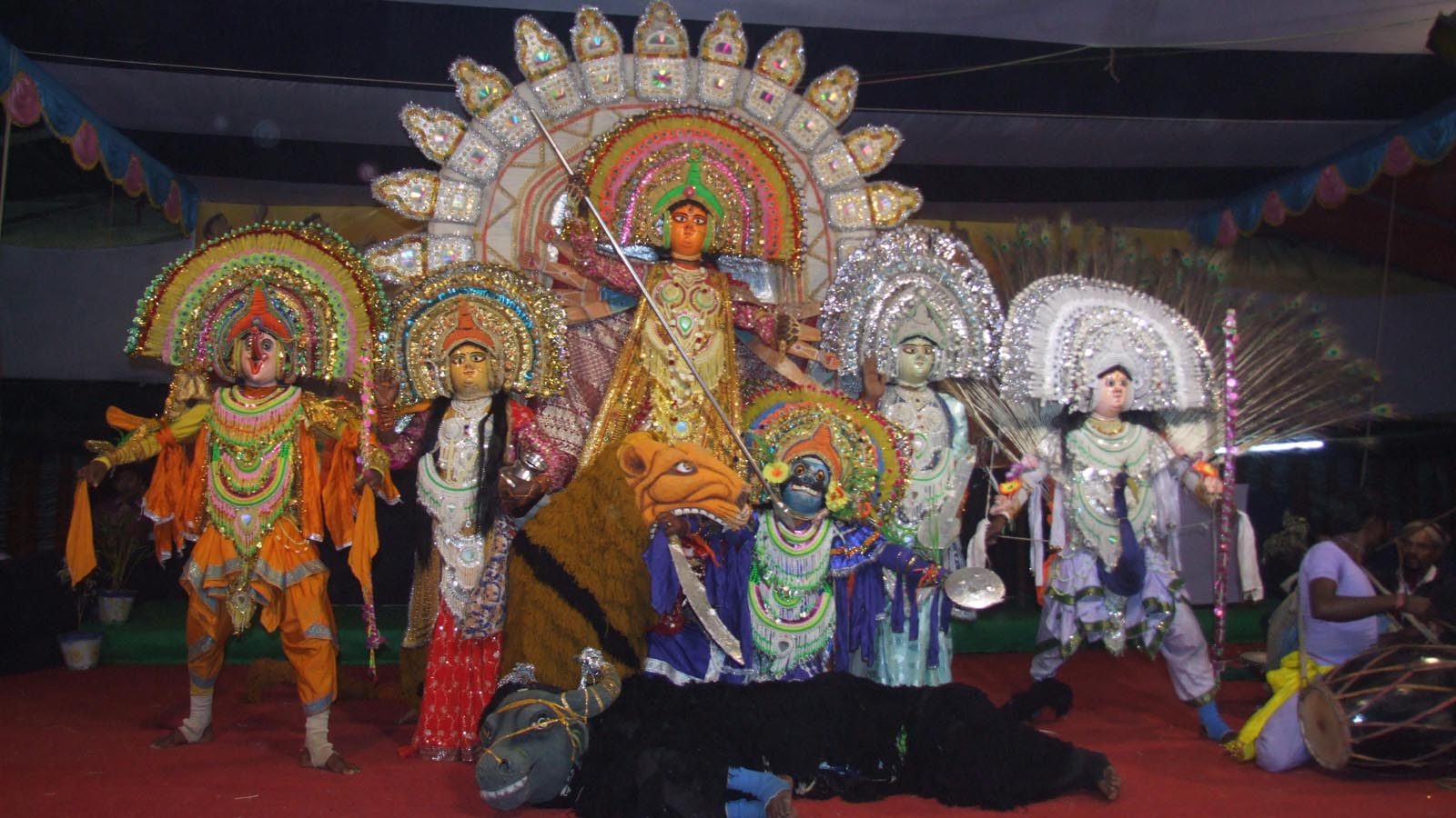 Students in elaborate Chhau-style costume performing a Durga tableau