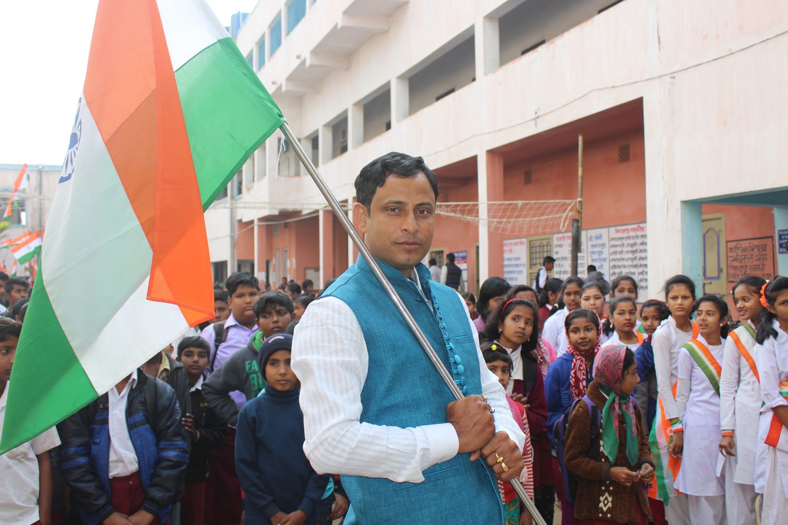 Headmaster holding the national flag, surrounded by students